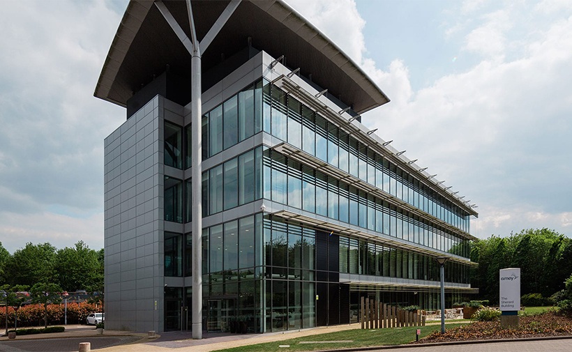 The Sherard Building is a striking, stand-alone building in the heart of the Oxford Science Park. The four-story building has been fully renovated to provide flexible office and laboratory space. In addition to the high-quality design of the suites, attention has also been paid to the practical environment of the building to meet tenant ‘back-of-house’ requirements. Outside, the building is surrounded by trees and greenery, creating a landscaped environment intended to promote sustainability and well-being for its occupants, with additional outdoor seating areas allowing for outdoor use. The current tenant is venture capitalist Oxford Science Enterprise (OSE). OSE uses the building to support life science start-ups arising out of Oxford University.