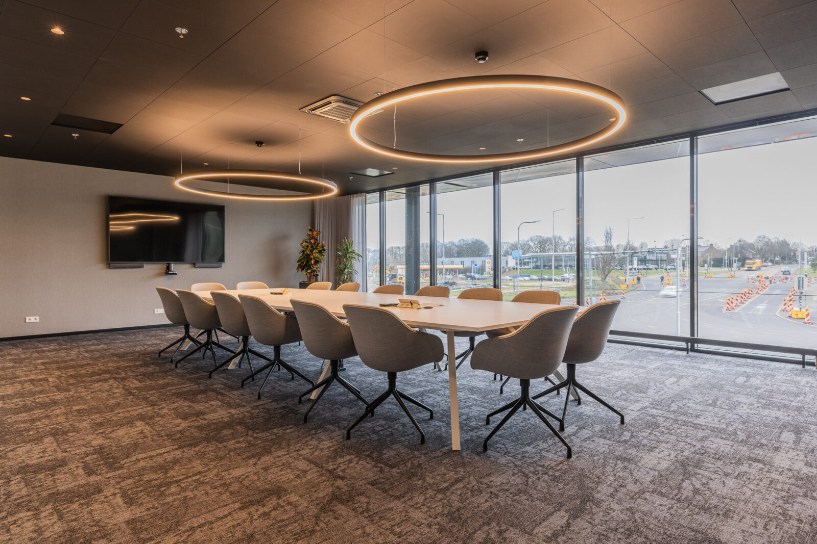 Modern conference room at Kadans Science Partner with circular pendant lights, large windows, and seating for twelve.