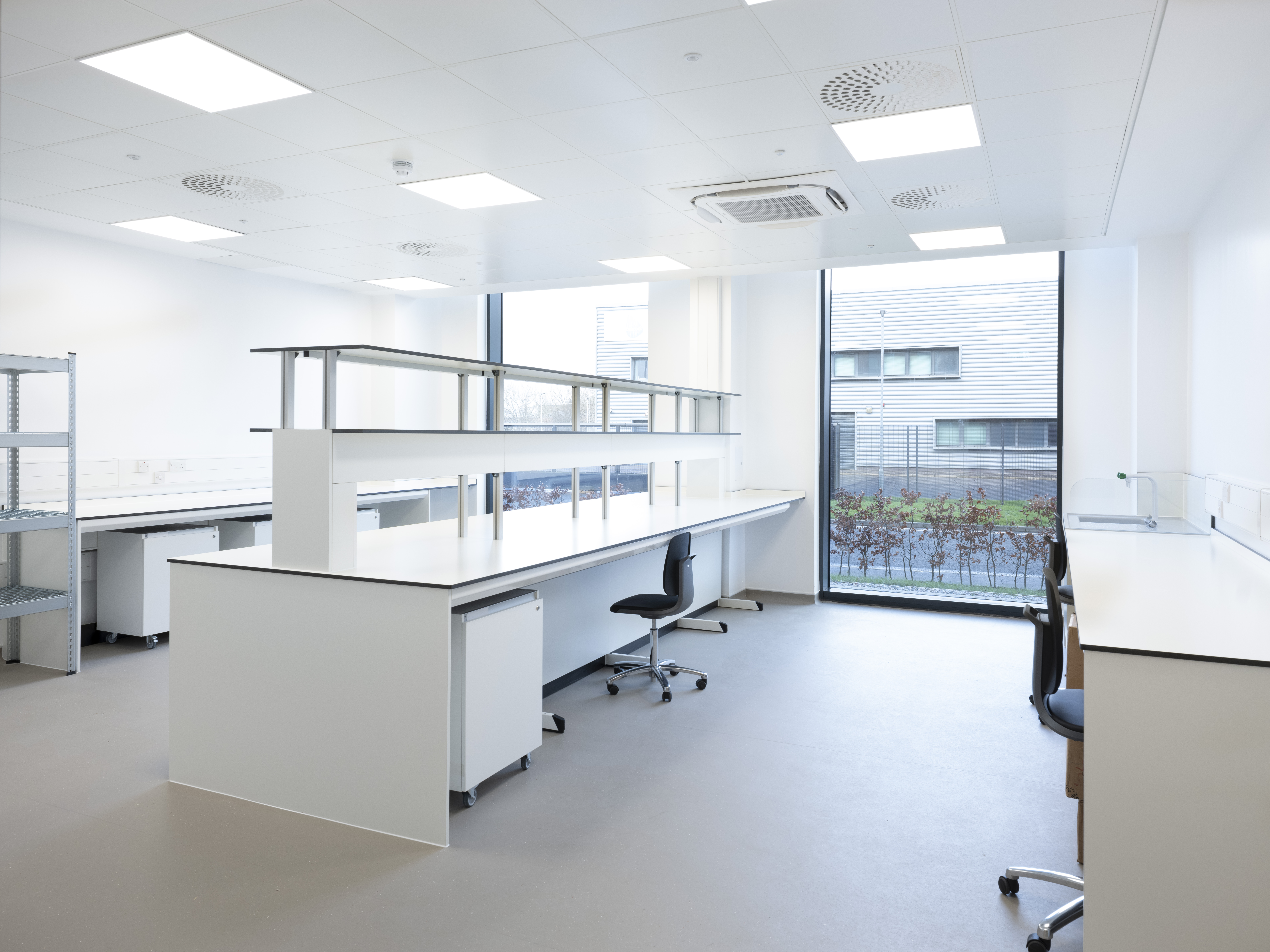 Modern laboratory interior with workbenches, chairs and natural daylight