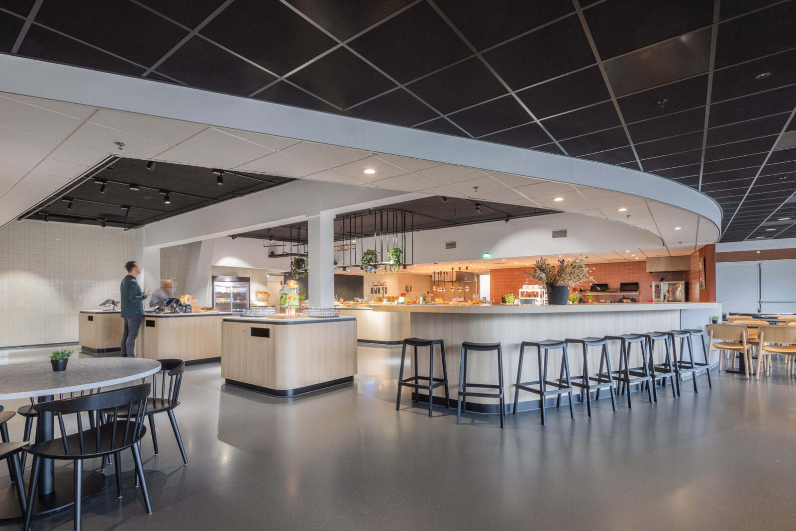 Restaurant at a Kadans Science Partner location with a buffet counter, bar seating, dining tables, and an open kitchen.