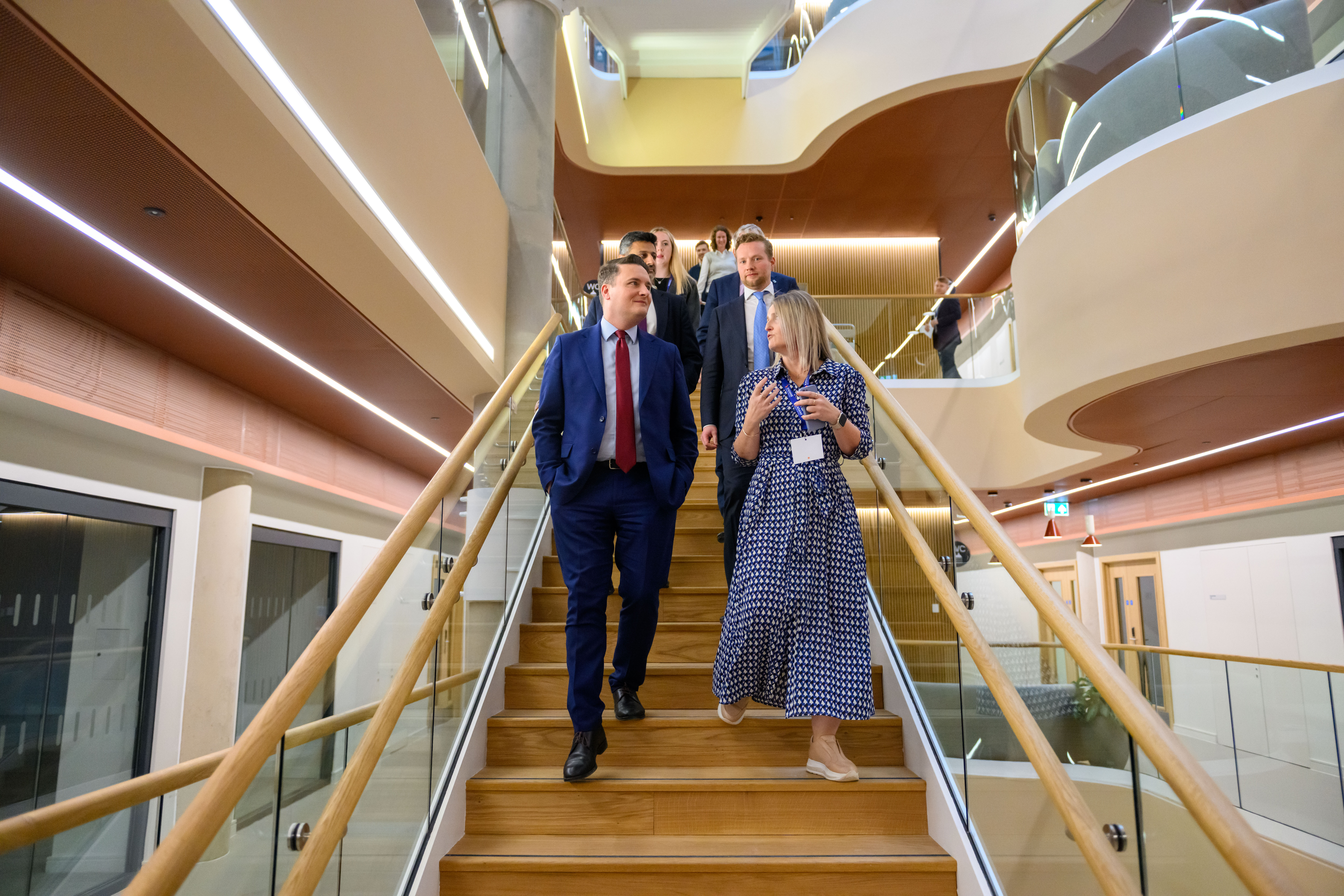 People walking down a staircase in a modern building - Kadans Science Partner