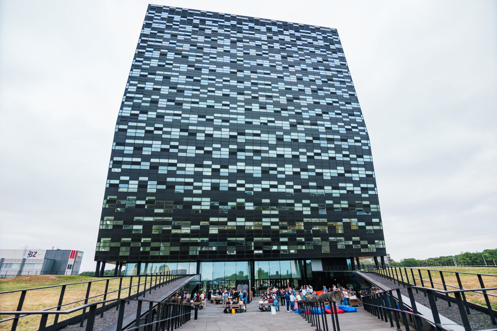 Exterior view of a Kadans Science Partner building in Nijmegen with a striking black facade and a lively community gathering at the entrance.